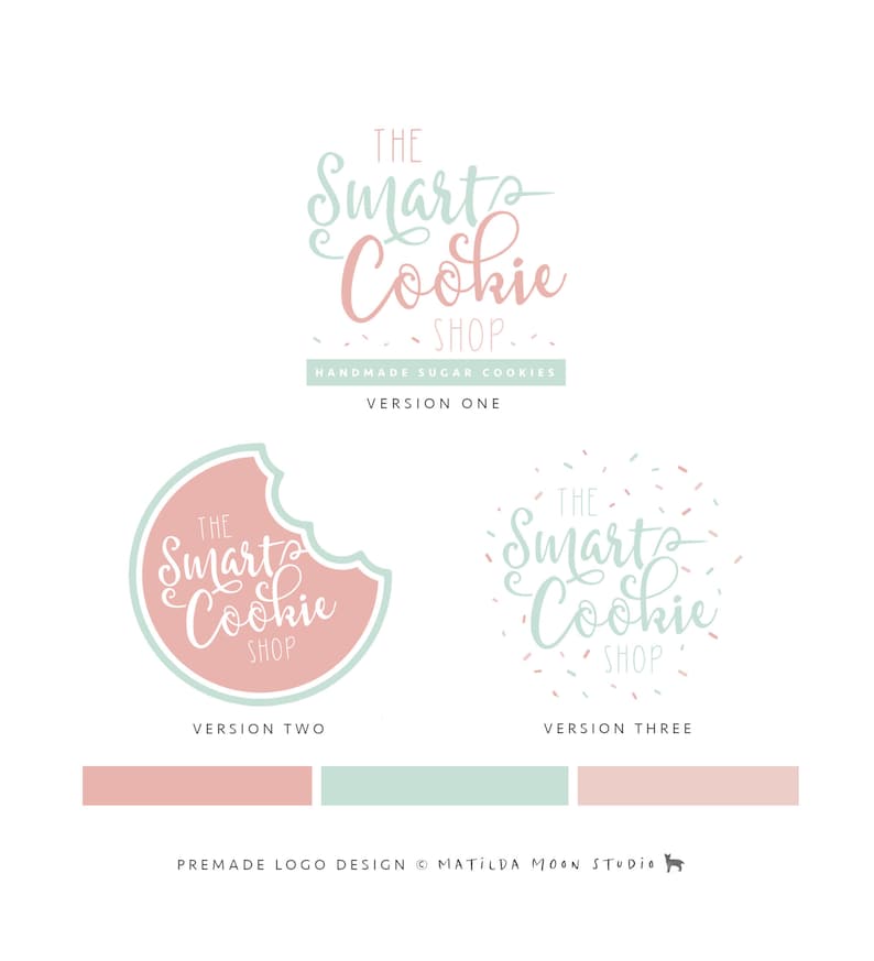 May include: Three logo variations for a cookie shop called "The Smart Cookie Shop". The first logo features the text in a script font with a pink and green color scheme. The second logo features the text in a script font inside a pink cookie with a bite taken out of it. The third logo features the text in a script font with pink and green sprinkles surrounding it.