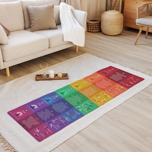 Peut inclure: Un tapis de yoga arc-en-ciel avec des illustrations de poses de yoga et des descriptions de chaque pose. Le tapis est posé sur un tapis blanc dans un salon.