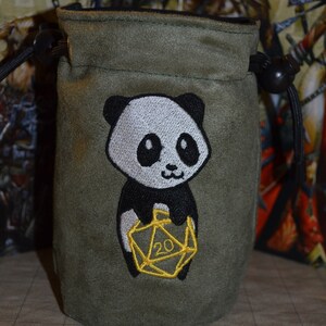 May include: A green dice bag with a black and white panda holding a gold 20-sided die.