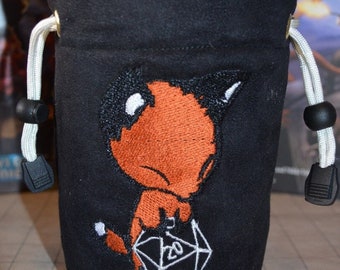 May include: Black dice bag with a white drawstring and a red and black embroidered fox holding a white 20-sided die.