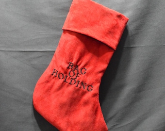 May include: A red Christmas stocking with the words "BAG OF HOLDING" embroidered in black. The stocking is hanging from a small hook.