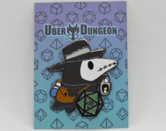 May include: A pin featuring a cartoon plague doctor with a black hat, white mask, and a green glitter D20 die. The pin has the text "Uber Dungeon" on a blue background with geometric shapes.
