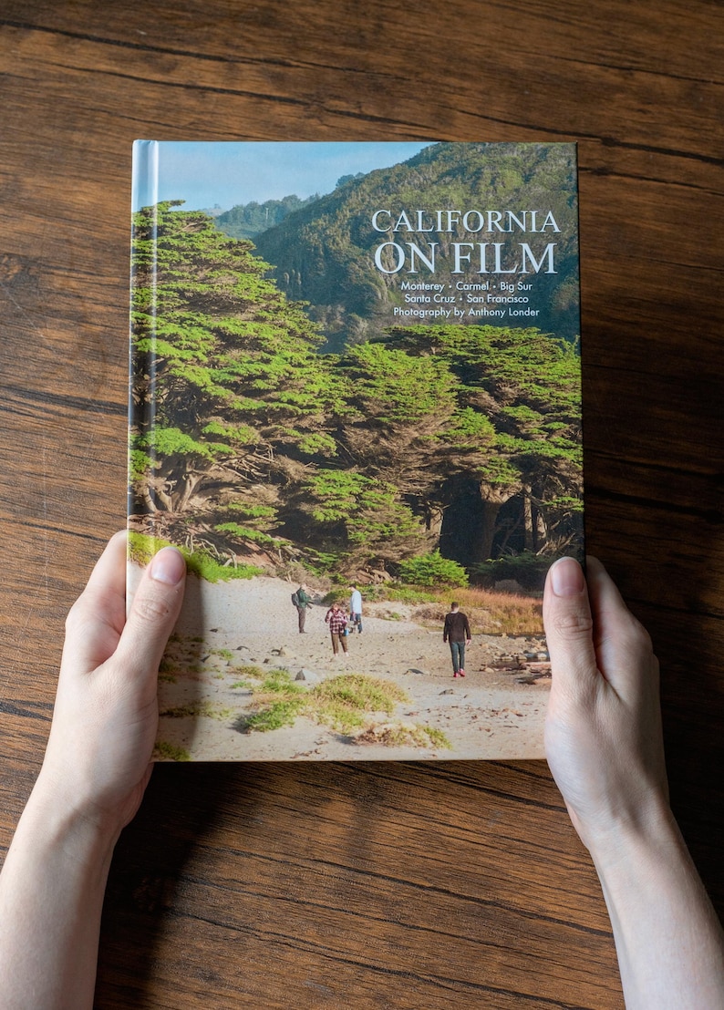 May include: A hardcover book titled California on Film, featuring photography by Anthony Londer. The cover displays a landscape image of a sandy beach with green trees and three people walking, with text listing Monterey, Carmel, Big Sur, Santa Cruz, and San Francisco.