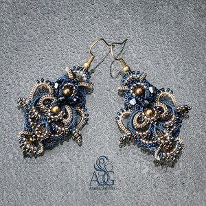 May include: A pair of intricate blue and gold earrings with a delicate, lacy design. The earrings are made with small beads and have a dangling, asymmetrical shape.