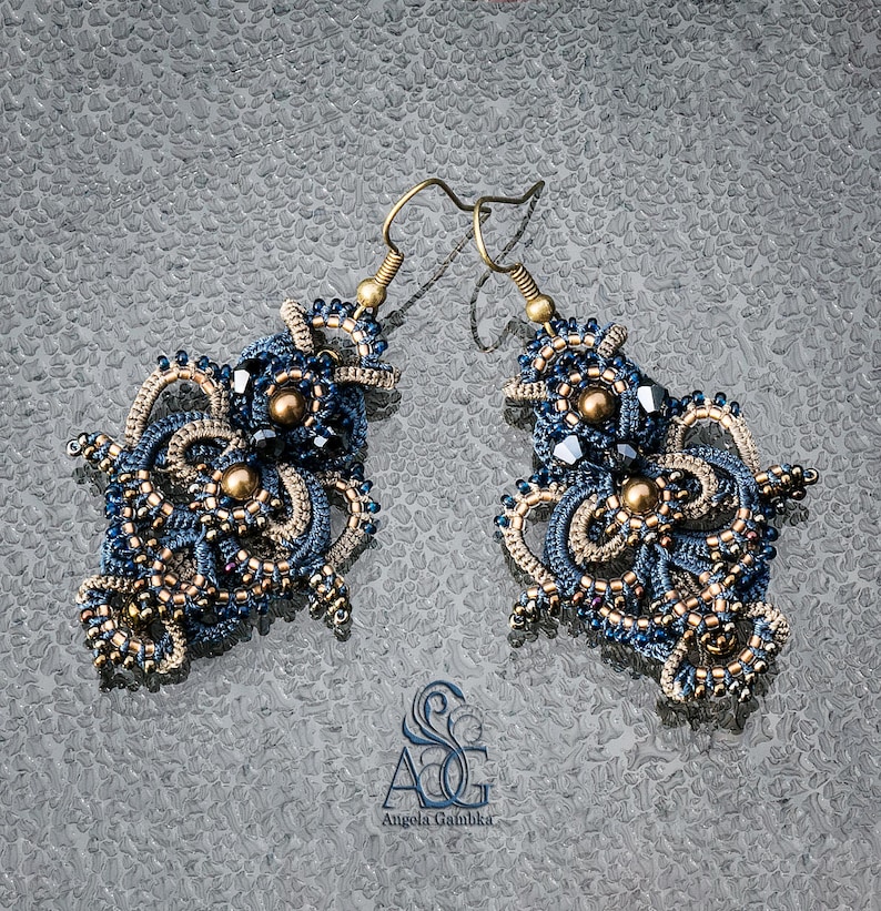May include: A pair of intricate blue and gold earrings with a delicate, lacy design. The earrings are made with small beads and have a dangling, asymmetrical shape.