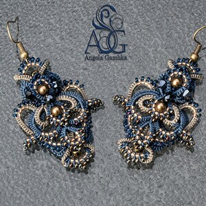 May include: A pair of blue and beige beaded earrings with gold accents. The earrings are intricate and detailed, with a delicate design. The earrings are hanging from gold hooks.