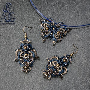 May include: A set of blue and gold jewelry featuring a pendant and earrings. The pendant is shaped like a butterfly and the earrings are teardrop shaped. The jewelry is made with intricate beadwork and has a delicate, feminine look.