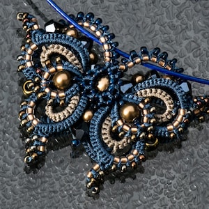 Puede incluir: Un colgante de mariposa azul y marrón con un cordón azul. El colgante está hecho de nudos y cuentas intrincados.
