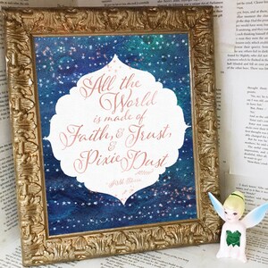 Puede incluir: Impresión enmarcada con la cita "All the World is made of Faith & Trust & Pixie Dust". La obra de arte presenta un fondo azul y turquesa estrellado. Una pequeña figura de Campanilla está a la derecha.