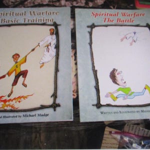 May include: Two books titled "Spiritual Warfare" with illustrations. The first book, "Basic Training," shows a figure being pulled by another figure. The second book, "The Battle," depicts a person on the ground. Both books have text and are framed.