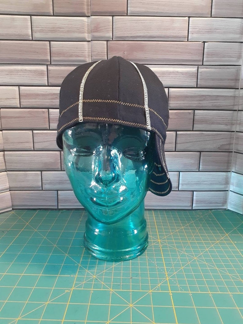 May include: A black cycling cap with white and yellow stitching. The cap is on a blue mannequin head.