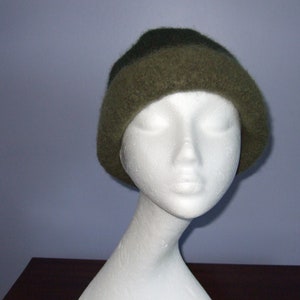 May include: A green and brown knit beanie hat on a white mannequin head.