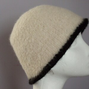 May include: A white knitted beanie with a black trim. The beanie is made of a soft, fluffy material.