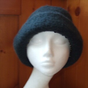 May include: A dark blue fuzzy beanie hat on a white mannequin head.
