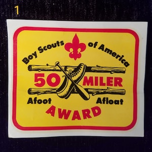 May include: Yellow and red Boy Scouts of America 50 Miler Award patch with a black and white illustration of a baseball bat and a hiking boot. The text "Afoot Afloat" is below the illustration.