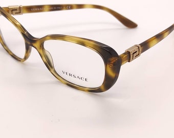 May include: Tortoise shell eyeglasses with a gold Versace logo on the arms and the word "VERSACE" printed on the right lens.