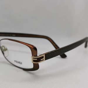 May include: Brown and gold rectangular eyeglasses with a FENDI logo on the side.