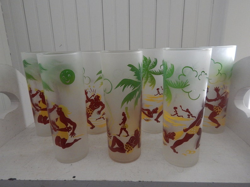 K&ouml;nnte beinhalten: Satz von acht gefrosteten Gl&auml;sern mit tropischem Thema. Jedes Glas zeigt eine gr&uuml;ne Palme, gelben Sand und braune Figuren in Badebekleidung. Ein Glas hat ein gr&uuml;nes Mondgesicht.