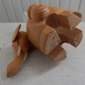 Puede incluir: Un elefante de juguete de madera de color marr&oacute;n claro. El elefante est&aacute; hecho de varias piezas de madera y tiene una superficie texturizada. El elefante est&aacute; de pie sobre sus patas traseras con sus patas delanteras levantadas en el aire.