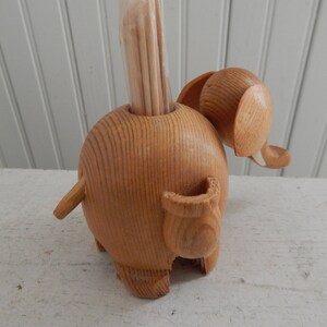 Puede incluir: Porta palillos de dientes de madera en forma de elefante con un acabado de madera natural. El elefante tiene una trompa larga y una cola peque&ntilde;a. El soporte est&aacute; dise&ntilde;ado para sostener los palillos de dientes en posici&oacute;n vertical.