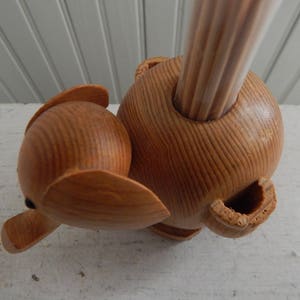 Puede incluir: Porta palillos de dientes de madera en forma de elefante con un acabado de madera natural. El porta palillos tiene un agujero en la parte superior para los palillos y un dise&ntilde;o de elefante tallado.