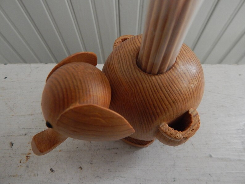Puede incluir: Porta palillos de dientes de madera en forma de elefante con un acabado de madera natural. El porta palillos tiene un agujero en la parte superior para los palillos y un dise&ntilde;o de elefante tallado.