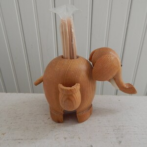 Puede incluir: Porta palillos de dientes de madera en forma de elefante con una bolsa de pl&aacute;stico transparente de palillos de dientes dentro.