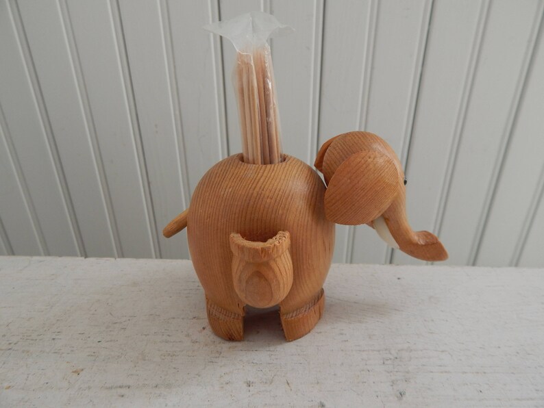 Puede incluir: Porta palillos de dientes de madera en forma de elefante con una bolsa de pl&aacute;stico transparente de palillos de dientes dentro.
