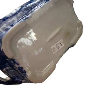 May include: A ceramic pitcher with a blue and white floral pattern. The pitcher has a rectangular shape with a handle and a white interior. The bottom of the pitcher is white with a sticker.