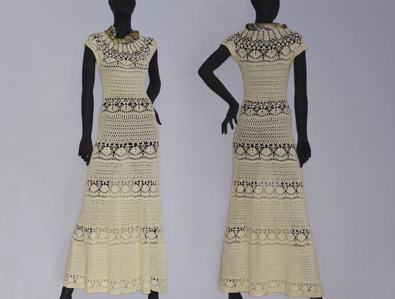 Pu&ograve; includere: Un lungo abito in crochet color crema con un delicato motivo floreale. L'abito ha un corpetto aderente e una gonna fluida con un orlo a balze.