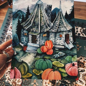 May include: Watercolor painting of a whimsical cottage with conical roofs, surrounded by pumpkins in shades of orange, green, and pink. The artwork features a detailed landscape with trees and mountains, evoking a fantasy theme.