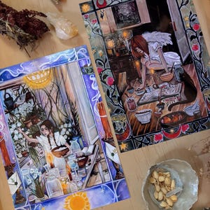May include: Two rectangular art prints featuring detailed illustrations of figures in interior settings. One print shows a person in a blue-toned room with plants and jars, while the other depicts a person with wings at a table with books and candles.