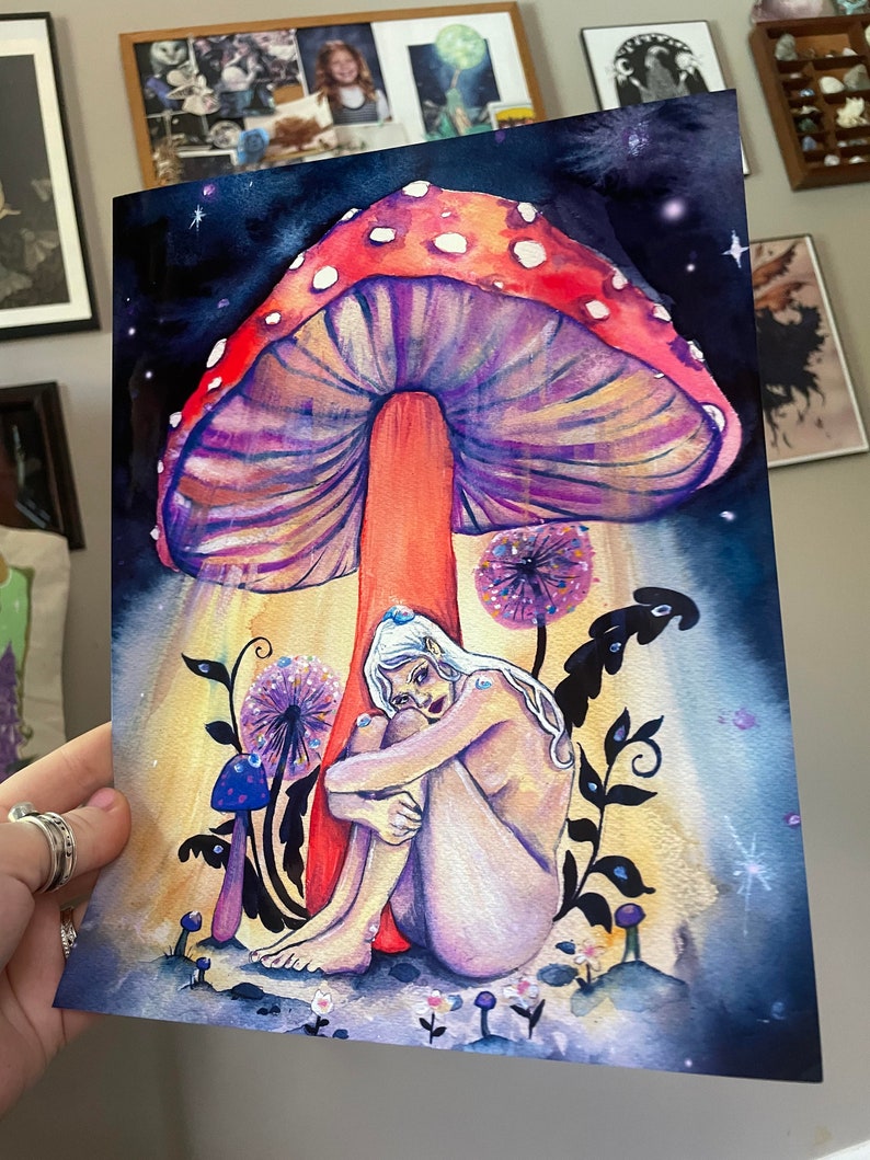 May include: A watercolor painting of a woman sitting under a large, red and purple mushroom with white spots. The woman is nude and has white hair and blue eyes. The background is a dark blue with white stars.