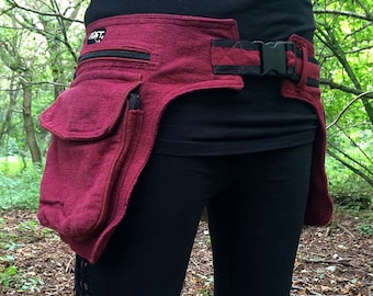 May include: A burgundy canvas belt with a black strap and buckle. The belt has multiple pockets and is worn around the waist.