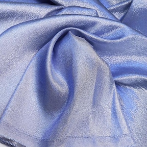 May include: A close-up of a light blue fabric with a subtle shimmer. The fabric is folded and draped, showcasing its texture and drape.