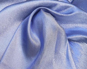 May include: A close-up of a light blue fabric with a subtle shimmer. The fabric is folded and draped, showcasing its texture and drape.