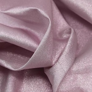 May include: Close-up of a soft, pink fabric with a subtle shimmer. The fabric has a smooth, silky texture and a delicate sheen.