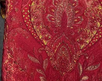 Könnte beinhalten: Roter Stoff mit goldfarbenem Paisley-Muster. Der Stoff hat eine strukturierte, fast samtige Haptik.