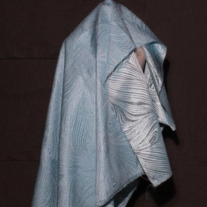 Puede incluir: Una tela azul claro con un diseño estampado blanco y azul claro. La tela está drapeada sobre una forma.