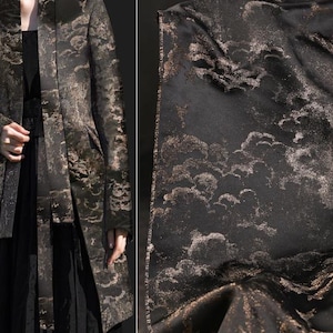 May include: A black long-sleeved jacket with a gold cloud pattern. The jacket has a shawl collar and a long, flowing silhouette.