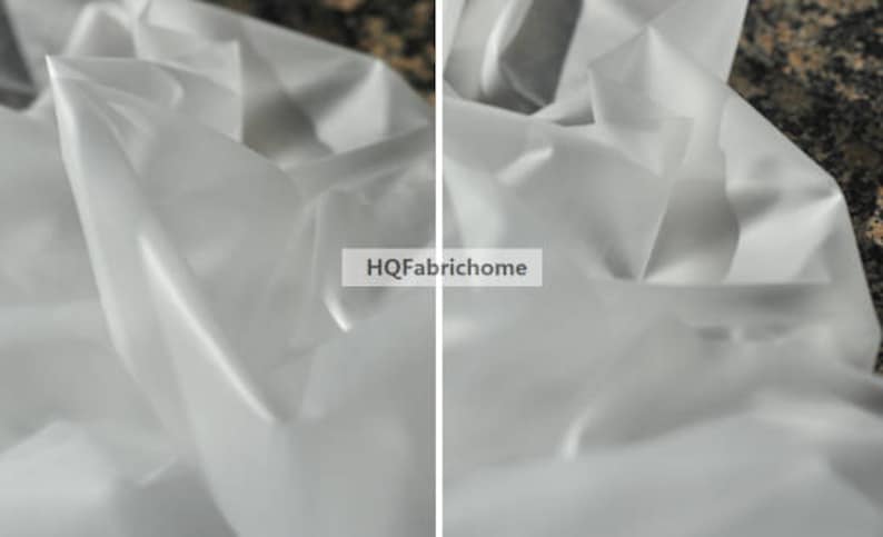 K&ouml;nnte beinhalten: Nahaufnahme eines wei&szlig;en, durchsichtigen Stoffes mit einer glatten, seidenartigen Textur. Der Stoff ist drapiert und gefaltet, wodurch weiche, flie&szlig;ende Linien entstehen. Der Stoff ist durchscheinend und l&auml;sst Licht hindurch.
