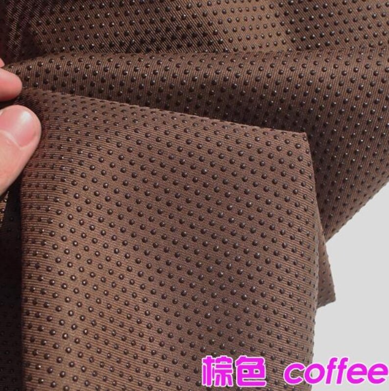 Pu&ograve; includere: Primo piano di un tessuto marrone con una superficie testurizzata di piccoli punti. Il tessuto &egrave; etichettato "棕色 coffee" in testo rosa.