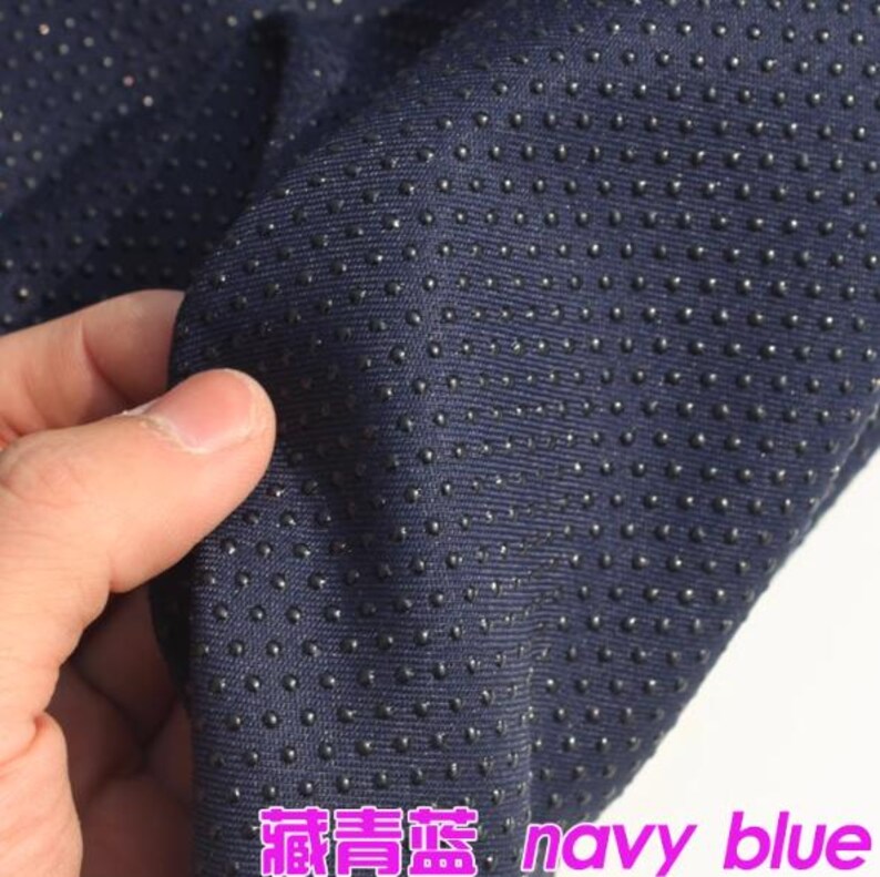 Pu&ograve; includere: Primo piano di un tessuto blu navy con una superficie testurizzata di piccoli punti in rilievo. Il tessuto &egrave; morbido e ha una leggera lucentezza.