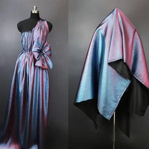 May include: A shimmering iridescent fabric in shades of blue and purple. The fabric is draped over a mannequin and has a subtle sheen.