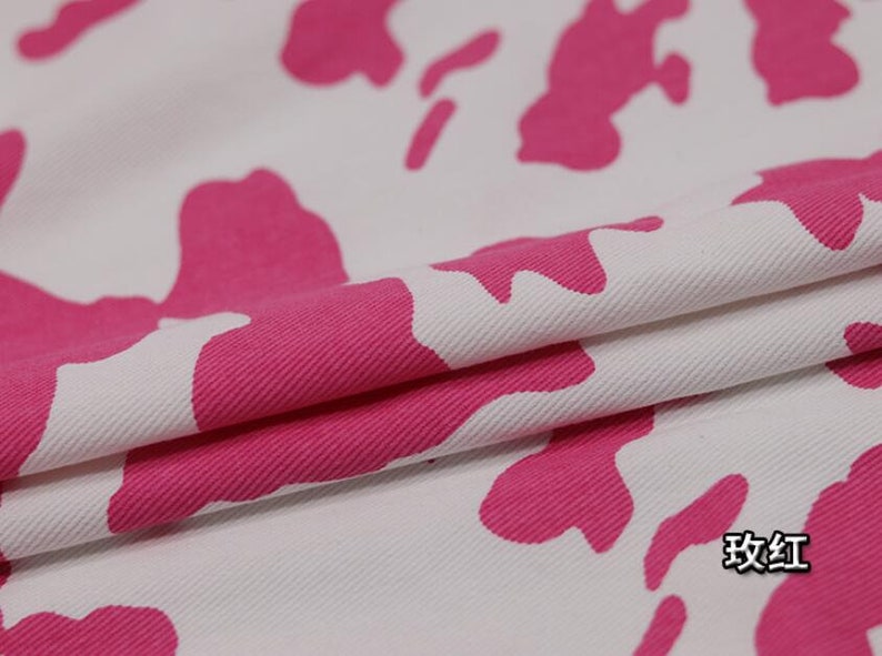 K&ouml;nnte beinhalten: Wei&szlig;er Stoff mit einem pinkfarbenen Kuhmuster. Der Stoff ist in der Mitte gefaltet und der Text "玫红" ist in der unteren rechten Ecke sichtbar.