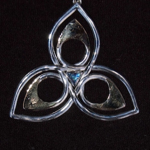 May include: Silver pendant with a Celtic knot design and a blue gemstone in the center.