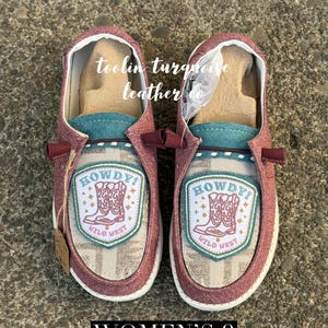 May include: Pair of maroon slip-on shoes with a turquoise accent and a "Howdy! Wild West" patch. The shoes have a white sole and are size 9.