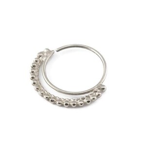 A silver-colored metal ring with a curved design and a row of small, round beads or stones attached to it.