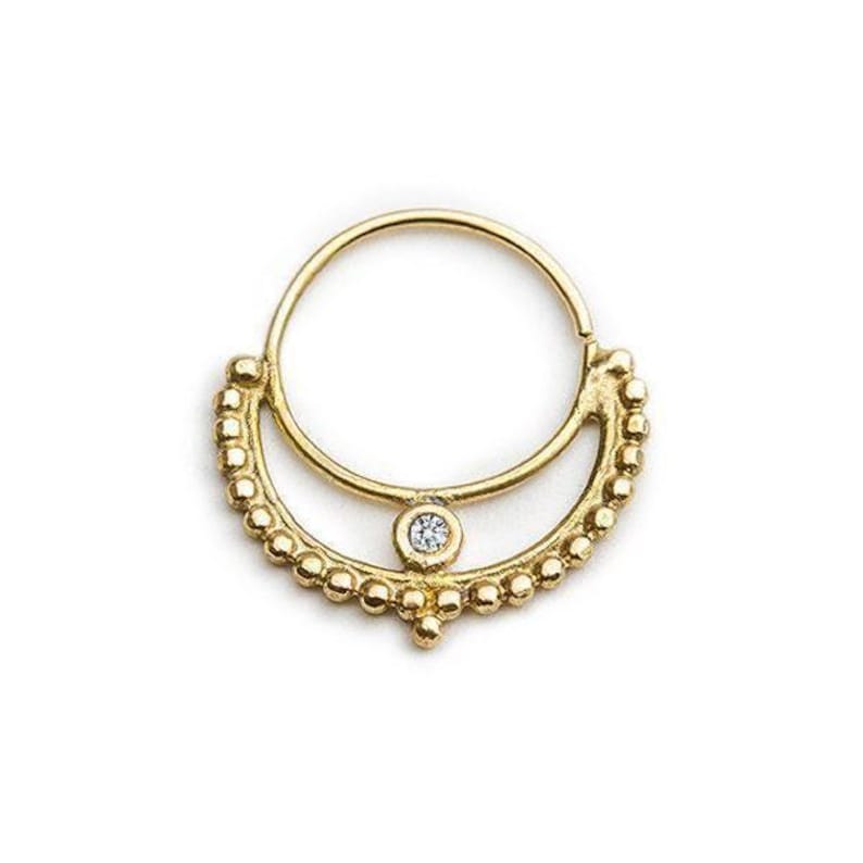 A gold-colored earring with a diamond at the center, featuring a decorative design with small beads around the outer edge.