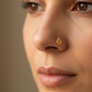 A close-up of a person's face, focusing on their nose and lips, with a gold nose stud visible
